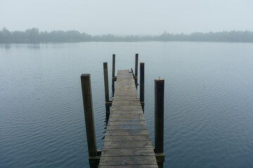 Narrow pier on the lake during morning fog