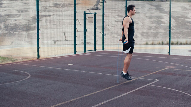 full length view of mixed race man jumping with skipping rope at outdoors gym.
