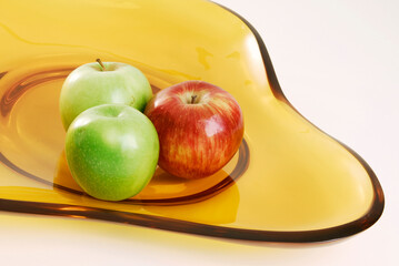 Amber glass fruit plate with three apples, isolated