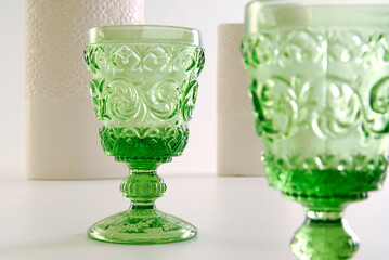 Detail of a pair of engraved green glass cups and a set of two white vases 