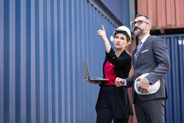 Senior manager businessman and businesswoman holding laptop computer with blue container ship