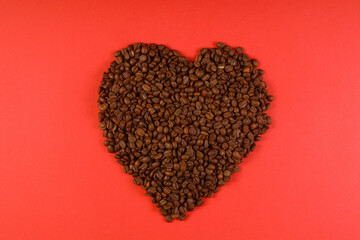 Heart coffee. Roasted coffee beans in the shape of heart on bright red background. Concept of coffee love, Valentines Day, good mood, gift