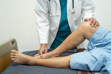 Obraz na płótnie Canvas Asian doctor physiotherapist examining, massaging and treatment knee and leg of senior patient in orthopedist medical clinic nurse hospital.
