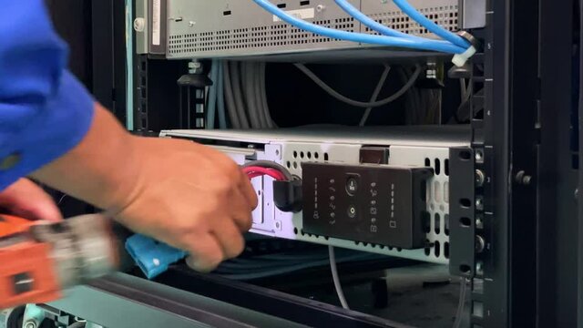 Technician installing and test UPS battery to electrical equipment control cabinet, technology and service working concept.