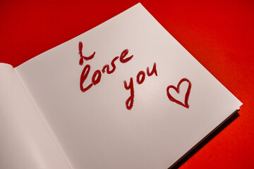 I love you. A declaration of love is written in lipstick on paper on a red background. Valentine's day card. High quality photo
