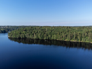 Aerial, drone photography of a sup board on a lake in summer time in Sweden. View of green trees and blue water and sky. Copy space and place for text.