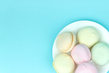 Sweet airy soft pastel and white marshmallows looks like macaroons lying on a plate, on a pastel background.