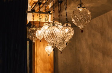 Glass chandeliers in intricate oriental shape with natural warm yellow light