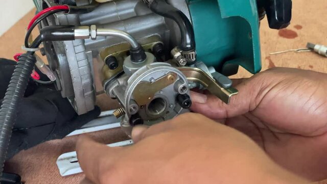A young man is repairing a small two-stroke engine used for farming. disassemble the parts cleaning the carburetor Reassemble and test 