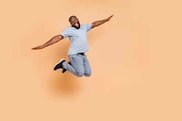 Fototapeta na wymiar Full length body size view of attractive cheerful guy jumping flying having fun isolated over beige pastel color background