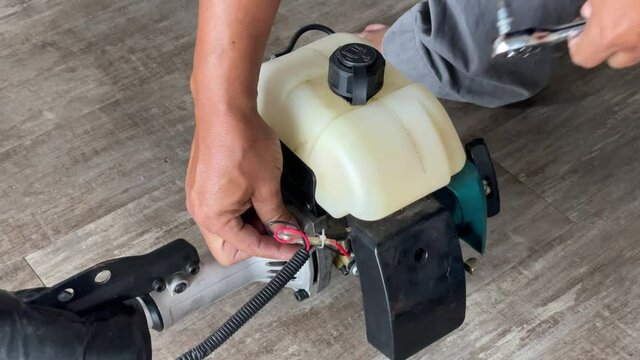 A young man is repairing a small two-stroke engine used for farming. disassemble the parts cleaning the carburetor Reassemble and test 