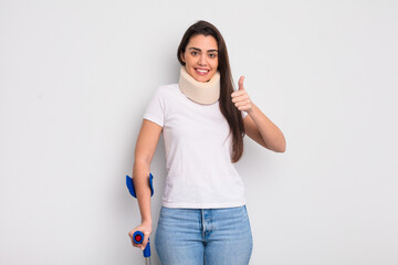 pretty hispanic woman feeling proud,smiling positively with thumbs up. crash and physical injury...