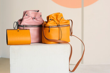 Fototapeta na wymiar orange purse, pink and yellow leather bag close up photo with copy space on white gray wall background