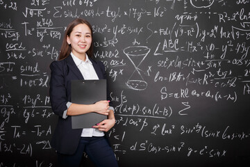 beautiful Asian schoolgirl stands with a folder near the school Board