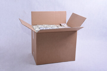 Cardboard packing box full of dollar bills on a white background
