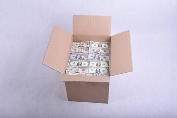 Cardboard packing box full of dollar bills on a white background