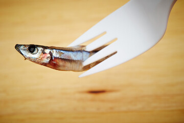 holding raw anchovies with a fork