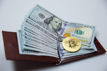 Gold bitkoyny and hundred-dollar bills in a leather purse. Bitcoin with a dollar in his wallet. fall of bitcoin