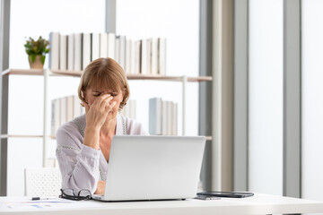 senior businesswoman or freelancer using laptop computer and headache at work