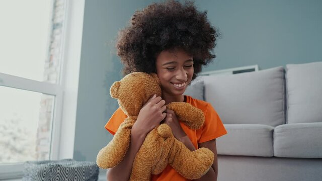 Cute child sit carpet play favorite toy hug embrace in living room flat 