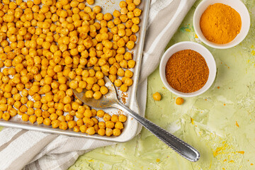 Indian traditional crispy, salty, savory snack - roasted chickpeas covered with spices curry powder, garam masala, and turmeric on a baking sheet. Flat lay, top view