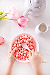 bowl with strawberry sweet corn balls. Delicious and healthy breakfast cereal. Kid hand take a spoon and eating