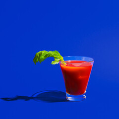 Small glass with cocktail bloody mary isolated on bright blue neon background. Concept of taste, alcoholic drinks