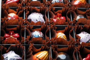 Fototapeta na wymiar Colorful handmade chocolates in a box on a dark background
