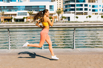 A young girl does a workout, runs on the street. Dubai Marina