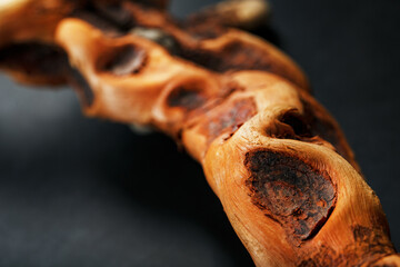 Textured curved Wooden snag of brown color with texture on a black background with free space.