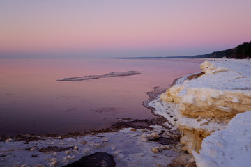 colorful beautiful sunset at sea in winter with snow on the beach