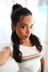 Confidence never looked this good. Cropped portrait of an attractive young blogger standing alone in her home and taking a selfie.