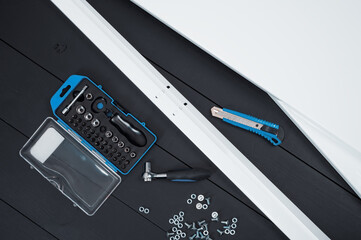 Flatlay keys, tools and with metal shelving on black wooden background