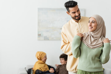 happy arabian man embracing muslim wife near blurred multiethnic family.