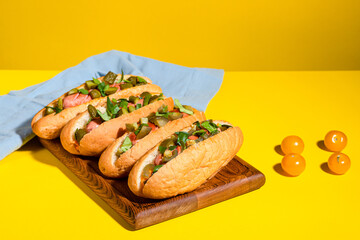Hot dog, hot dog with pickled cucumbers, jalapeno peppers, carrots, greens on a yellow background