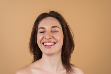 Close beauty portrait of a topless woman with perfect skin and natural makeup, shiny lips, on a beige background