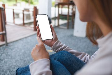 Mockup image of a woman holding and using mobile phone in the outdoors