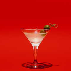 Martini glass with olives isolated on bright red neon background with shadow. Concept of taste, alcoholic drinks