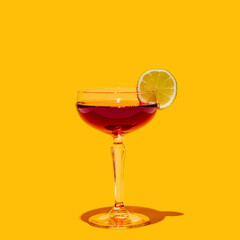 Glass with manhattan cocktail isolated on bright yellow neon background. Concept of taste,...