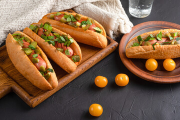 Hot dog, hot dog with pickled cucumbers, jalapeno peppers, carrots, greens on a black background
