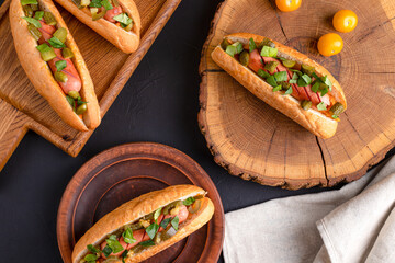 Hot dog, hot dog with pickled cucumbers, jalapeno peppers, carrots, greens on a black background