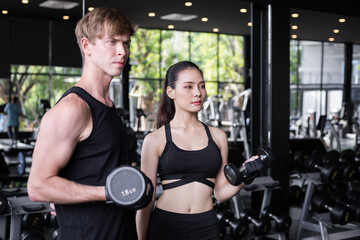 Fototapeta premium Young couple with dumbbells in the modern gym.