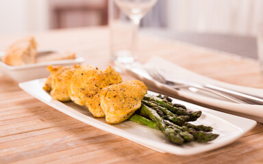fried chicken breast pieces with asparagus on white plate