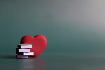 Bibliophile, book lover concept. Stack of books and red heart with copy space for text
