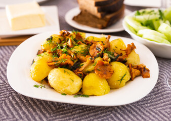 baked potatoes with chanterelles, served with herbs on white plate