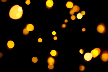 Gold bokeh on dark background. Defocused golden lights. New Year, Christmas background, abstract texture