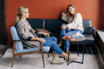 Relaxed young woman talking with therapist in a cozy office. Pleasant conversation between two women