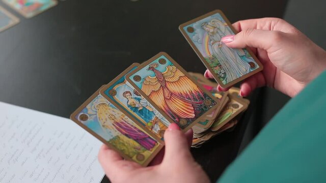 Female hands hold tarot cards. Divination in the occult. Predict the future. Meaningful pictures are drawn.