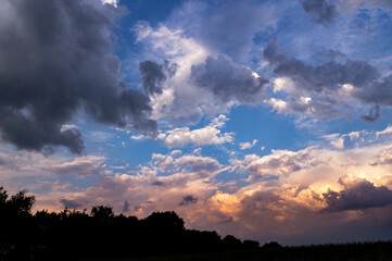 Colourful autumn evening landscape with dramatic cloudy sunset sky above the field with crops