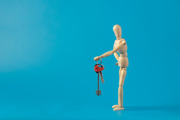 Little wooden man holds the keys to the house.  Investing in real estate and buying a house. Real estate and mortgages.  Concept for buying and renting house. Copy space.